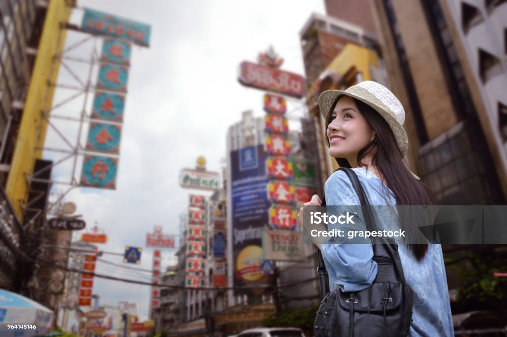 Young asian woman traveler with a backpack on her shoulder and travel hat walking on footpath over China town, Bangkok, Thailand, Travel holiday relaxation concept Asia Stock Photo