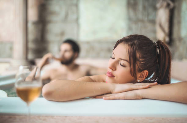 mulher jovem e bonita relaxante na banheira de água quente com o marido. - couple hot tub spa treatment health spa - fotografias e filmes do acervo