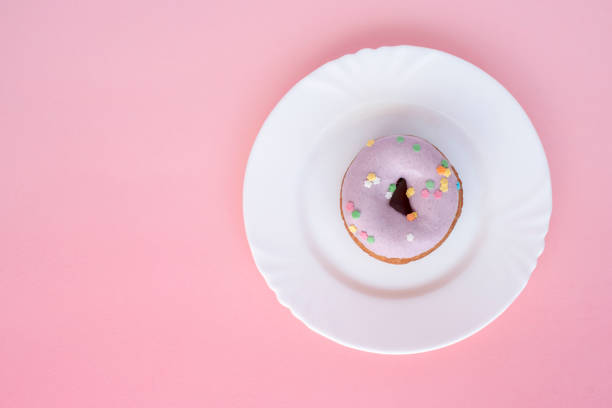 istock A donut covered in purple frosting on a white plate 964154680