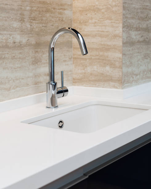 istock Detail of a white rectangular designer kitchen sink with chrome water tap against a tiled wall 964155860