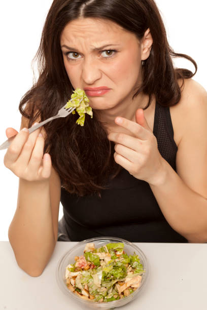 istock disgusted woman eating a caaesar salad to go on white background 964156028
