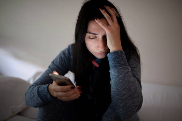 istock Woman sitting alone and depressed looking at phone 964158544