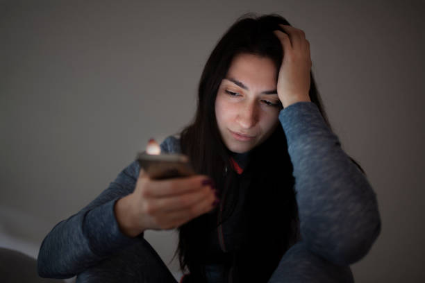 istock Woman sitting alone and depressed looking at phone 964158828