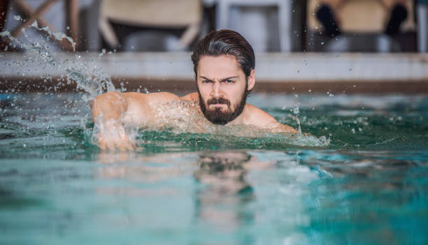 grave joven hombre nadando en la piscina. - sports venue luxury love enjoyment fotografías e imágenes de stock