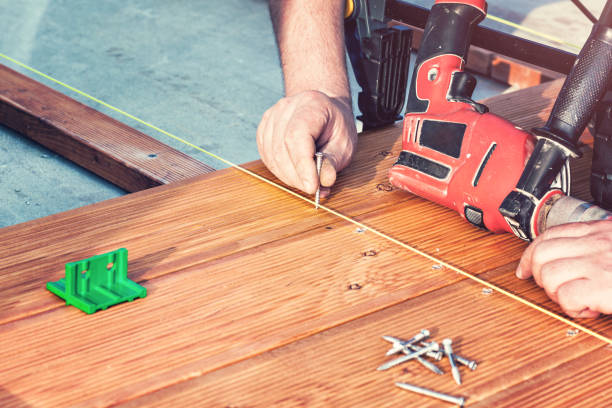 istock Construction worker screwing down wood deck with battery power screw gun or drill. 964159706
