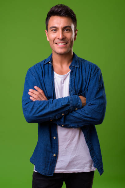 istock Young handsome Hispanic man against green background 964162290