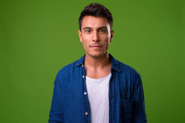 istock Young handsome Hispanic man against green background 964163066