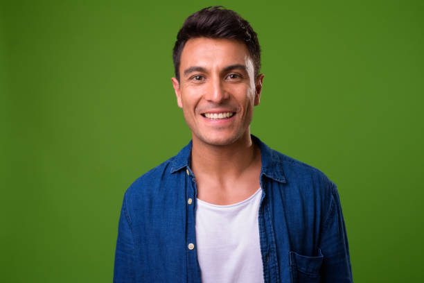 Young handsome Hispanic man against green background