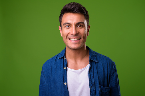 Studio shot of young handsome Hispanic man against chroma key with green background