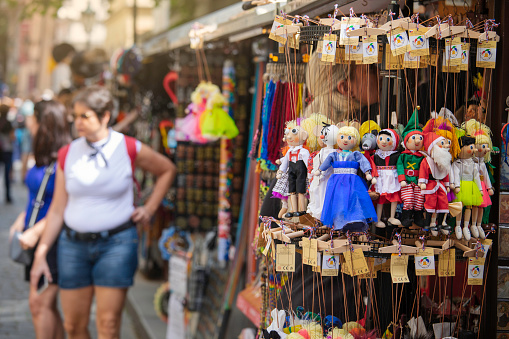 A market stall with czech souvenir puppets in a city street with various stalls offering merchandise and souvenirs.