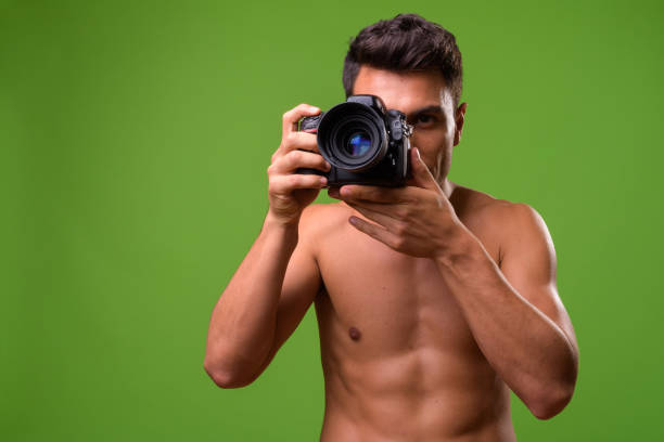 istock Young handsome Hispanic man shirtless against green background 964164848