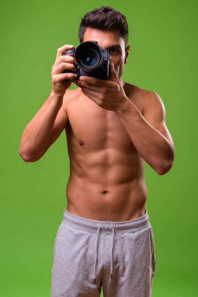 istock Young handsome Hispanic man shirtless against green background 964166876