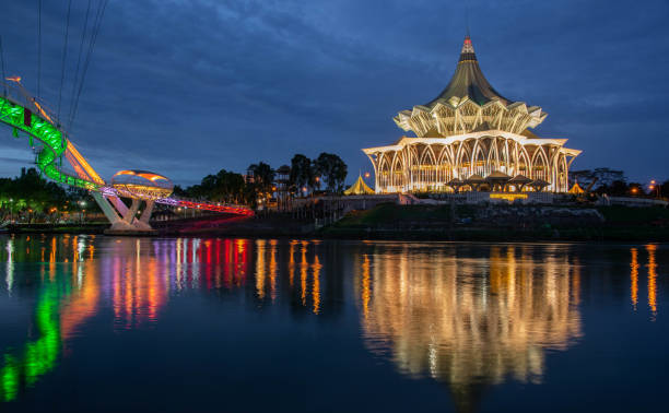 Sarawak River waterfront at Kuching Borneo The riverfront at Kuching, Malaysia including pedestrian bridge and National Assembly Building kuching waterfront stock pictures, royalty-free photos & images