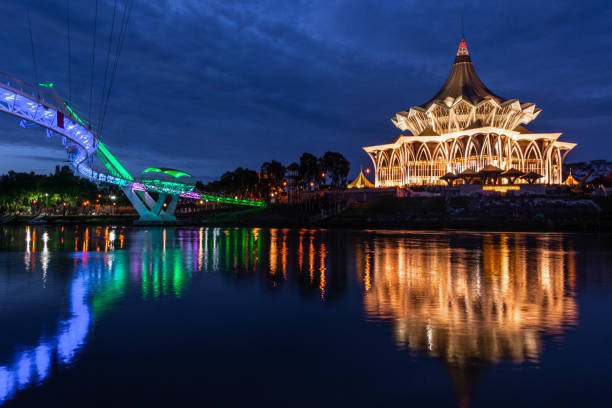 Sarawak River waterfront at Kuching Borneo The riverfront at Kuching, Malaysia including pedestrian bridge and National Assembly Building kuching waterfront stock pictures, royalty-free photos & images