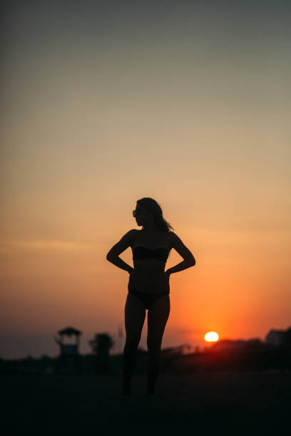 istock Beautiful girl sunbathing on a sandy beach. sunset silhouette 964172582