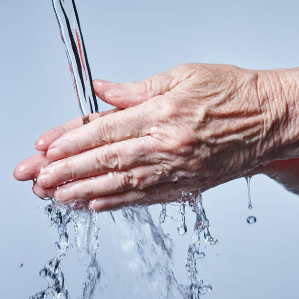 istock Washing hands: senior person's hands being washed under running water 964172930