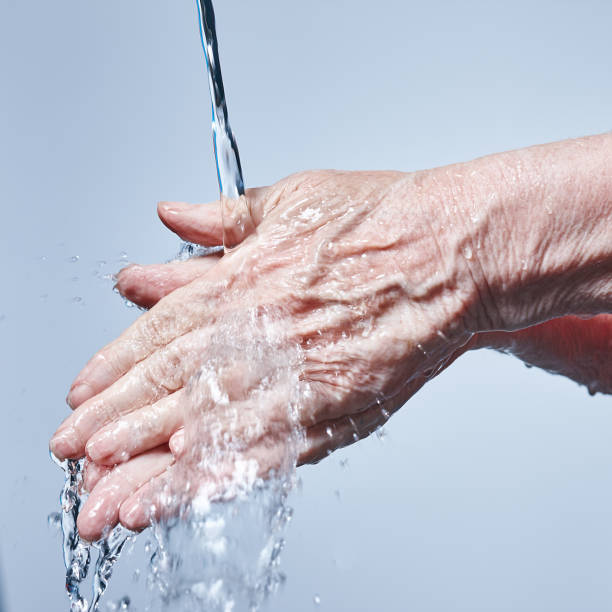 istock Hand washing: Senior woman's hands being washed under running water 964175652