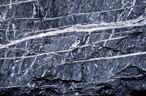 istock Granite stone scratched wall background grunge texture rough. Abstract construction concrete stone wall. Mountain rock or volcano stone. Cool and chic adventure wallpaper. Black and white color. Close up. 964175922