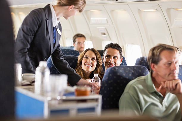 flight attendant serving customers on an airplane - tripulação imagens e fotografias de stock