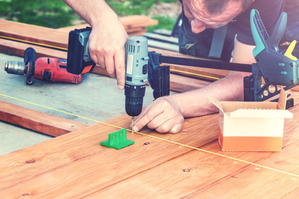 istock Construction worker screwing down wood deck with battery power screw gun or drill. 964176970