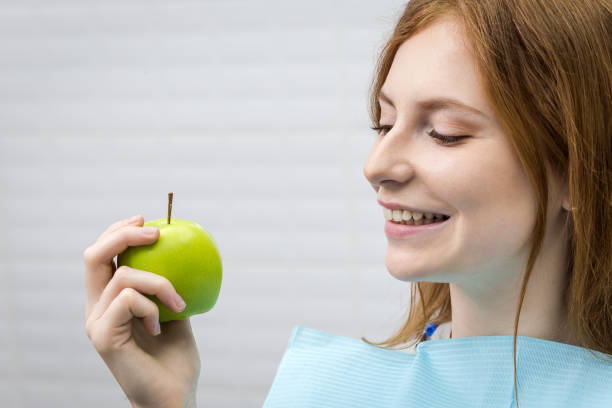 istock Young woman with healthy tooth biting green apple 964179892