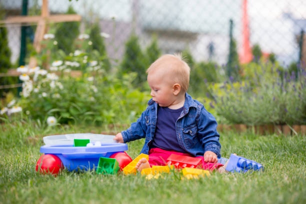 istock Little baby boy, playing with big construction blocks in garden 964185992
