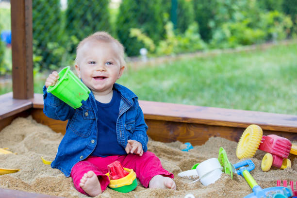 istock Little baby boy, playing in a sandpit with different toys 964187084