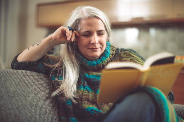 mujer madura en su casa - women book mature adult reading fotografías e imágenes de stock