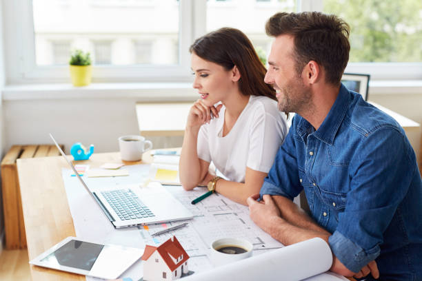 istock Two designers architects working together with laptop sitting at table 964191092