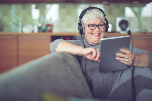 mujer senior en casa escuchando música - surfista de plata fotografías e imágenes de stock