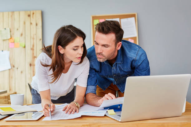 istock Busy couple working at the office counting financial data 964191928