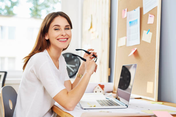 istock Successful female architect designer sitting at table with laptop and blueprints 964194622
