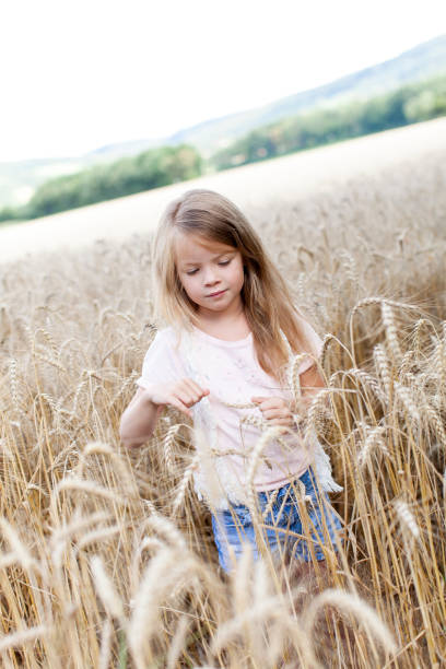istock Cute Girl Standing Amidst Wheat Plants Against Sky 964195584