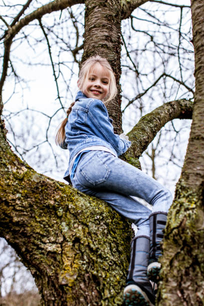 istock Low Angle Portrait Of Girl On Bare Tree 964200600