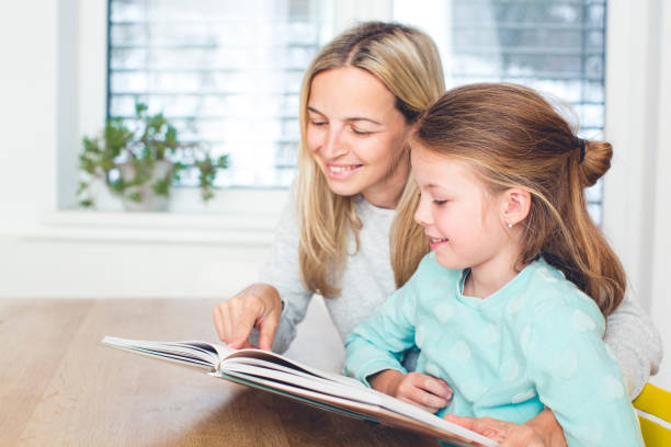 istock Girl With Mother Reading Book At Home 964200828