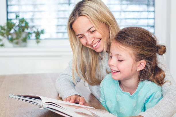 istock Girl With Mother Reading Book At Home 964200848