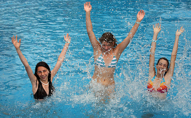 Four young adults having fun playing chicken in a swimming pool during summer vacation