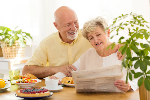 istock Happy senior woman reading newspaper during breakfast with smiling husband 964204158