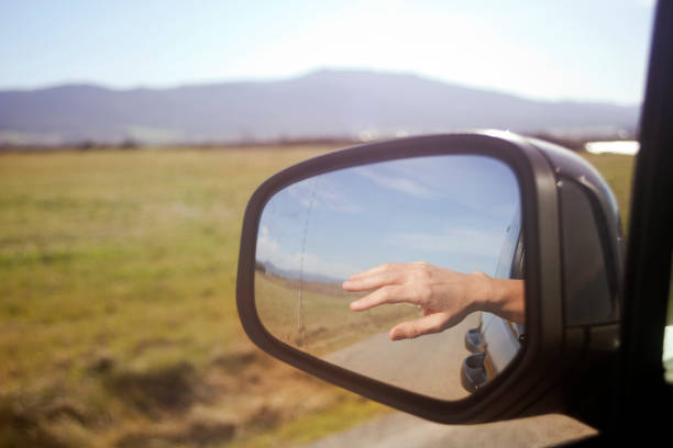 istock Driving on country road, rear-view mirror, hand reflected. 964209560