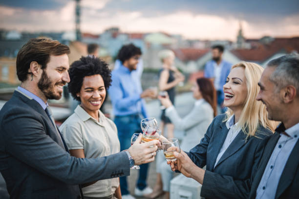 Cheerful business colleagues toasting with alcohol at the outdoor party. Group of happy business people having fun while toasting with alcohol at the outdoor party. after work stock pictures, royalty-free photos & images