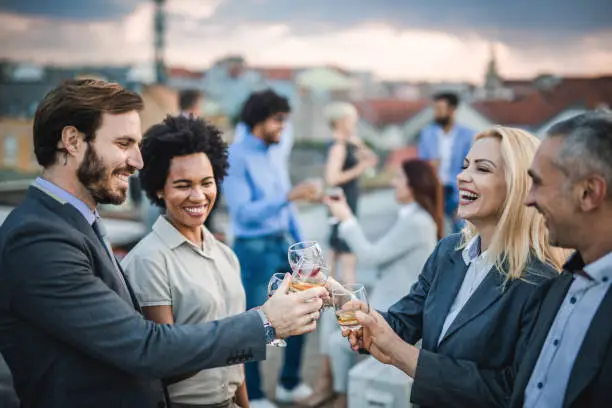 Photo of Cheerful business colleagues toasting with alcohol at the outdoor party.