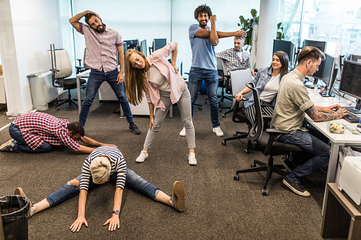 Young computer programmers doing stretching exercises on a break in the office.