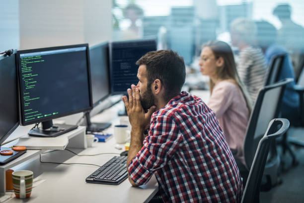 worried programmer having problems while working on new computer program in the office. - looking through window businessman problems reading imagens e fotografias de stock