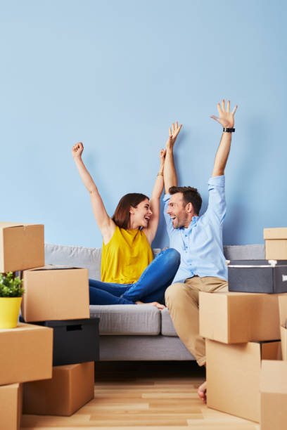 pareja excitada hacia nuevo apartamento - women moving house men relocation fotografías e imágenes de stock