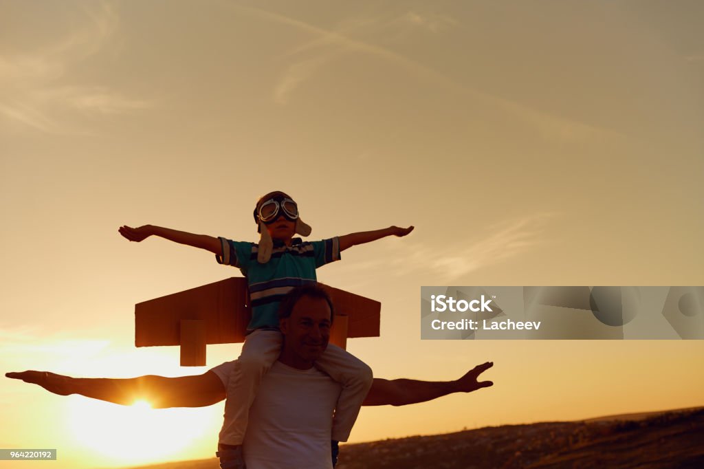 Father and son  at sunset in natur Father and son in a pilot's suit with wings  at sunset in nature. Father's Day Stock Photo
