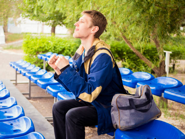 fã de masculino jovem sozinho torcendo para seu time favorito, sentado na tribuna - red white american football stadium soccer stadium - fotografias e filmes do acervo