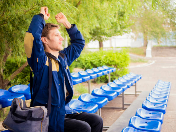 fã de masculino jovem sozinho torcendo para seu time favorito, sentado na tribuna - red white american football stadium soccer stadium - fotografias e filmes do acervo