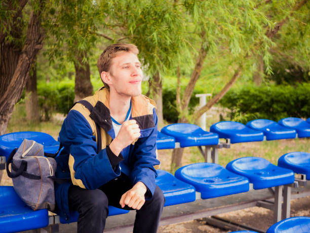 fã de masculino jovem sozinho torcendo para seu time favorito, sentado na tribuna - red white american football stadium soccer stadium - fotografias e filmes do acervo