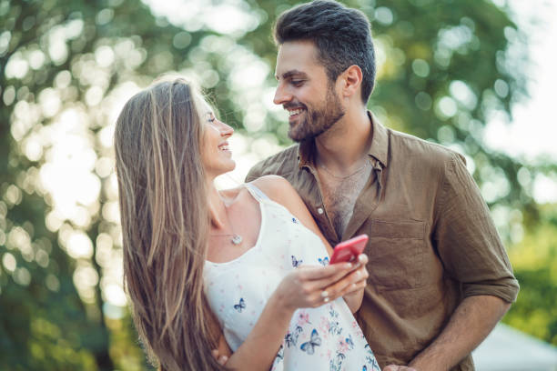 istock Young woman texting on her phone while meeting her boyfriend 964233848