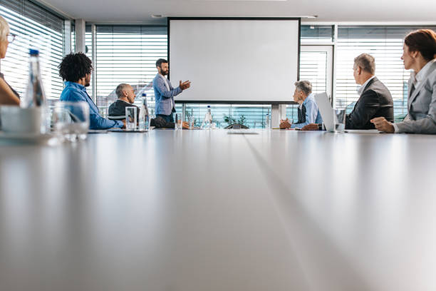 CEO giving a business presentation through projection screen in a board room.